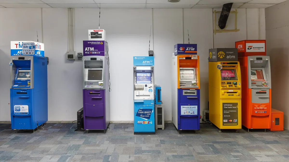 Colourful ATMs of several Thai banks lined up against a wall at Phuket International Airport