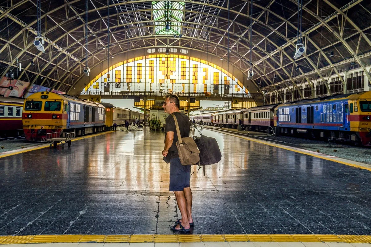 Foreign backpacker with a shoulder bag standing on the platform under the arched hall of Hua Lamphong station, Bangkok