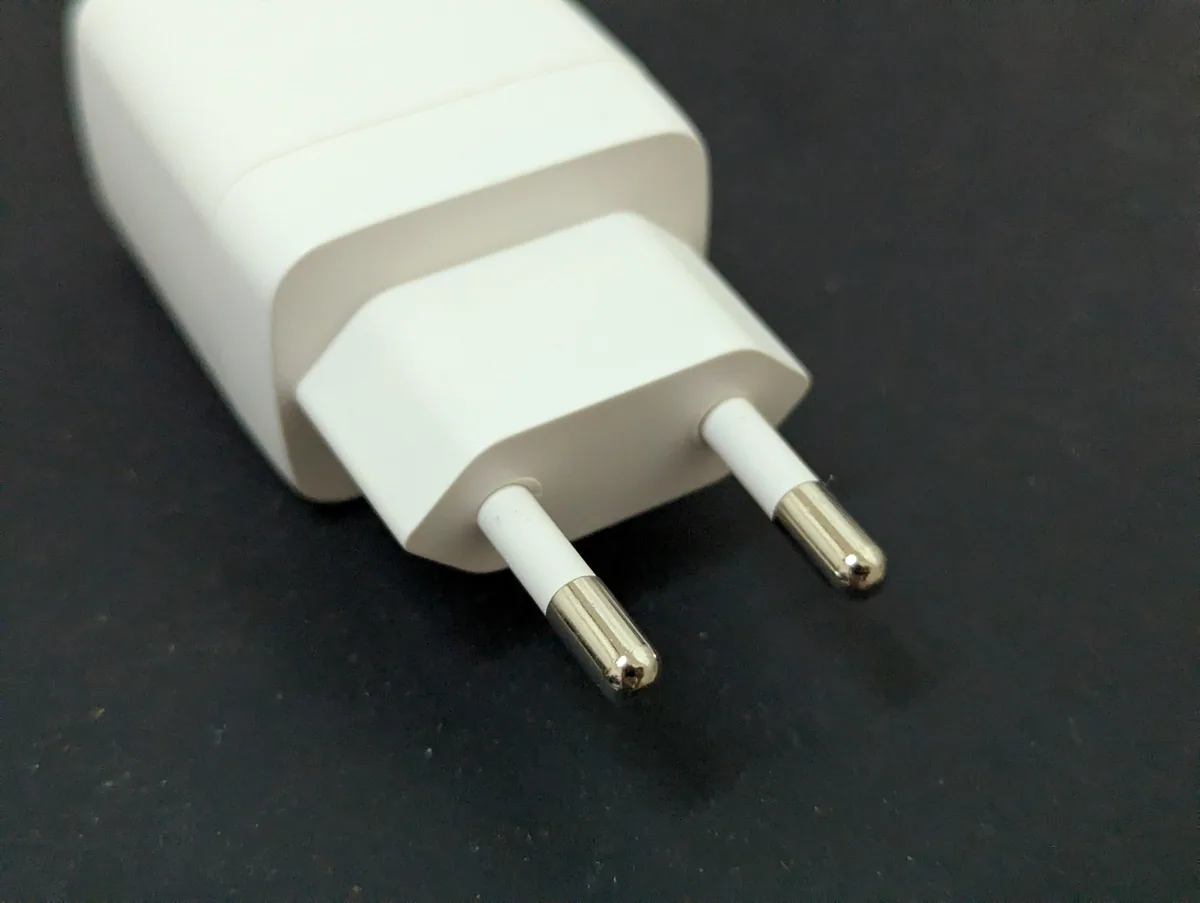 Close-up of a white charger with the two round pins of the Thai standard TIS 166-2549 plug