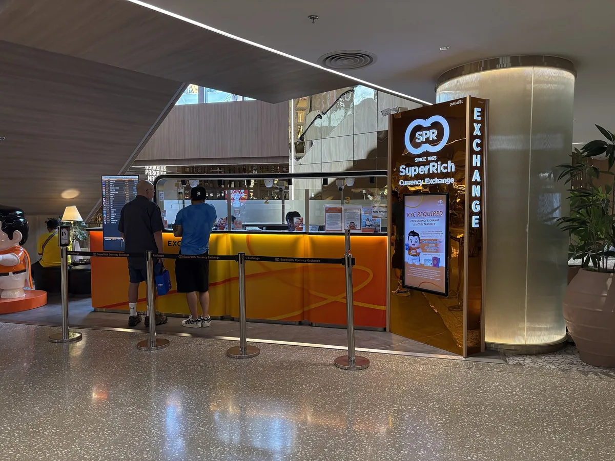 Customers queuing at a SuperRich currency exchange counter in a Bangkok shopping mall