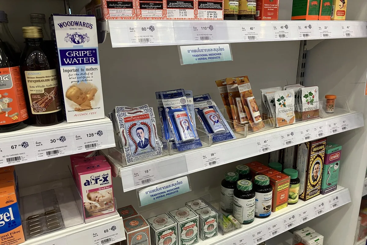 Packets of cough pills, herbal remedies and gripe water lined up on a Thai drugstore shelf