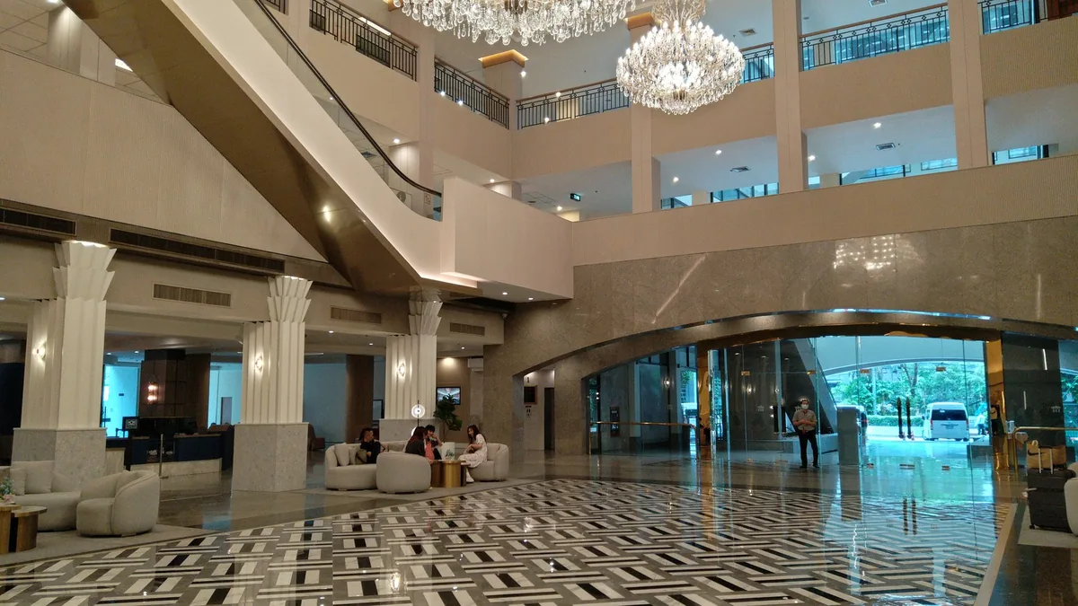 The marble lobby of the Twin Towers Hotel in Bangkok, with seating areas and the entrance doors