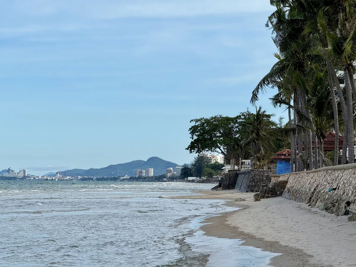 Palm-lined Cha-am beach with the high-rises of Hua Hin and its headland across the bay