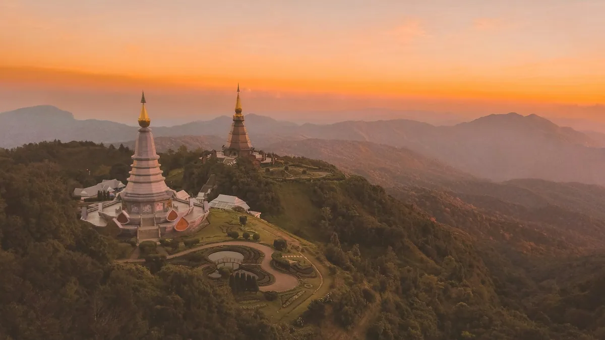 Twin chedis on Doi Inthanon overlooking forested mountain ridges at sunset in northern Thailand