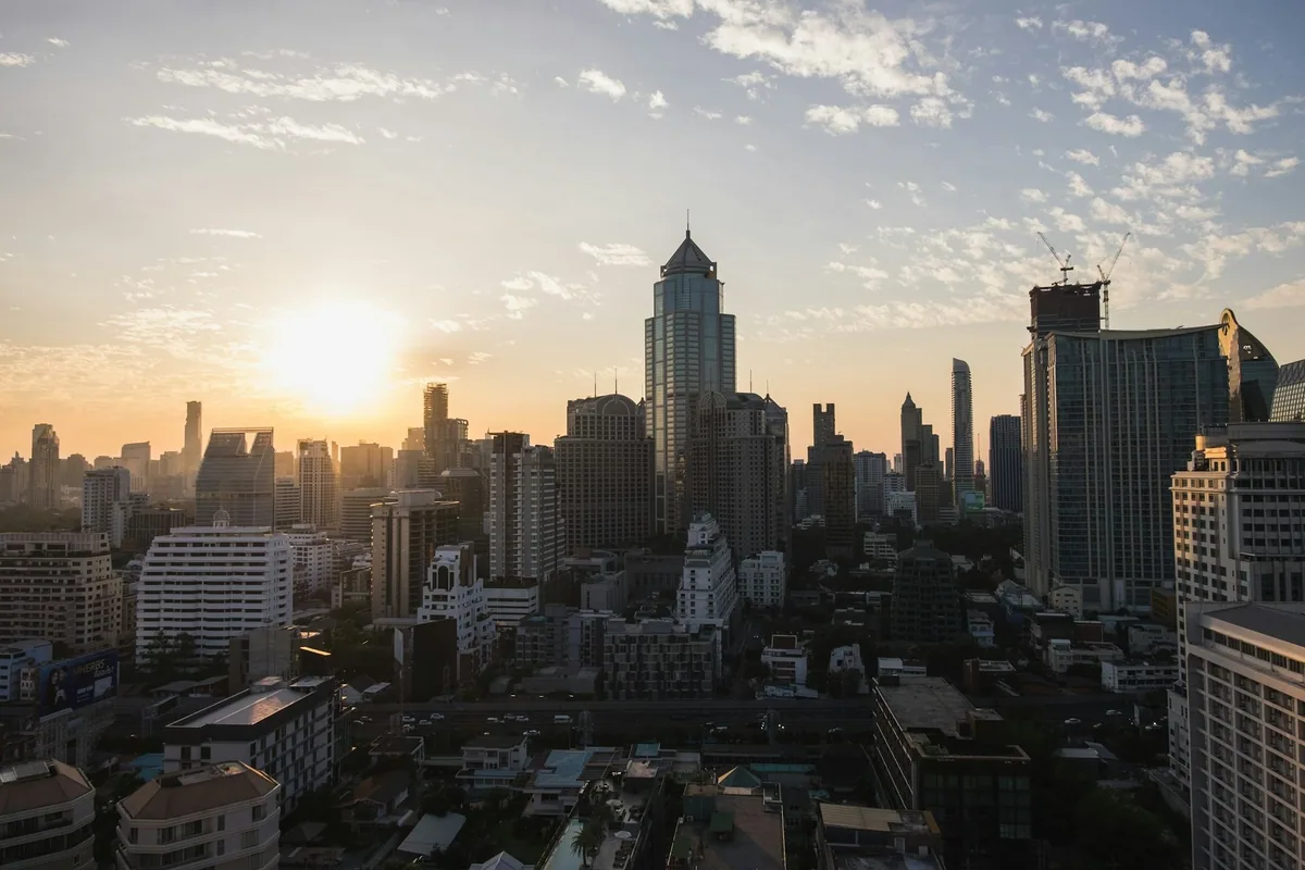 Sun setting behind high-rise towers of the Bangkok skyline