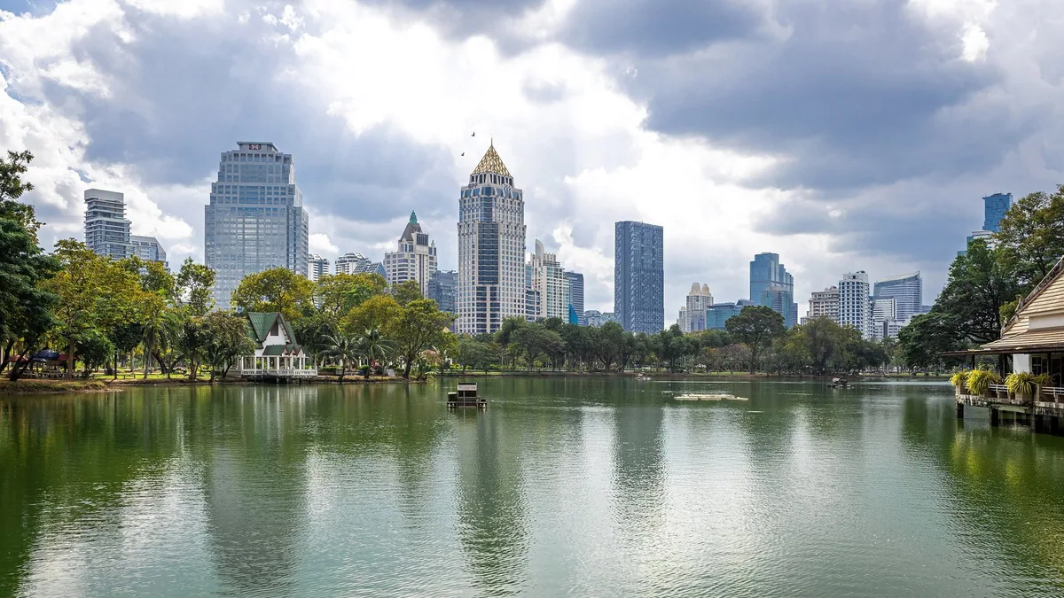 The lake in Lumphini Park with Bangkok's office towers rising behind the trees