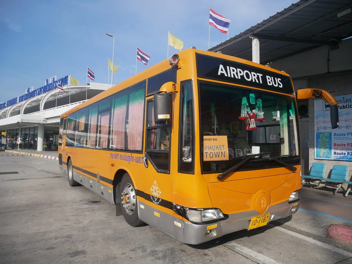 Orange airport bus parked outside the terminal building at Phuket International Airport