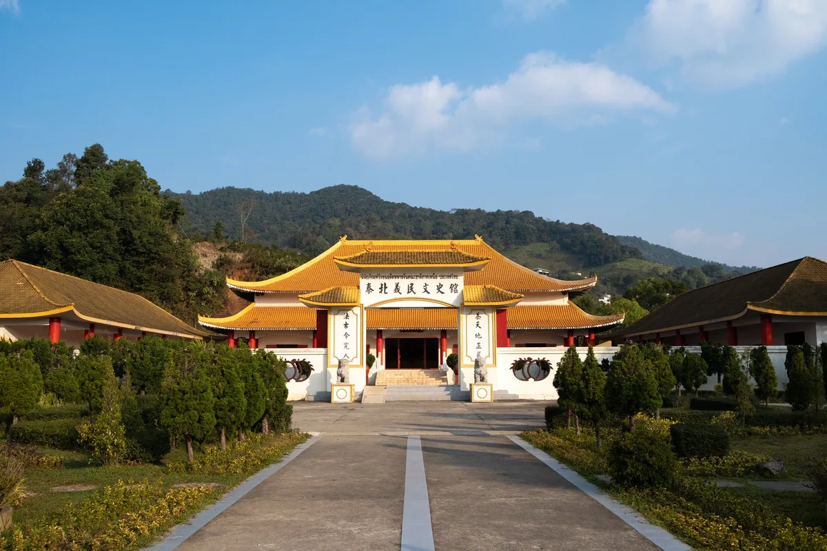 Yellow-roofed Chinese-style Martyrs' Memorial Hall of the KMT 93rd Division set against forested hills in Mae Salong