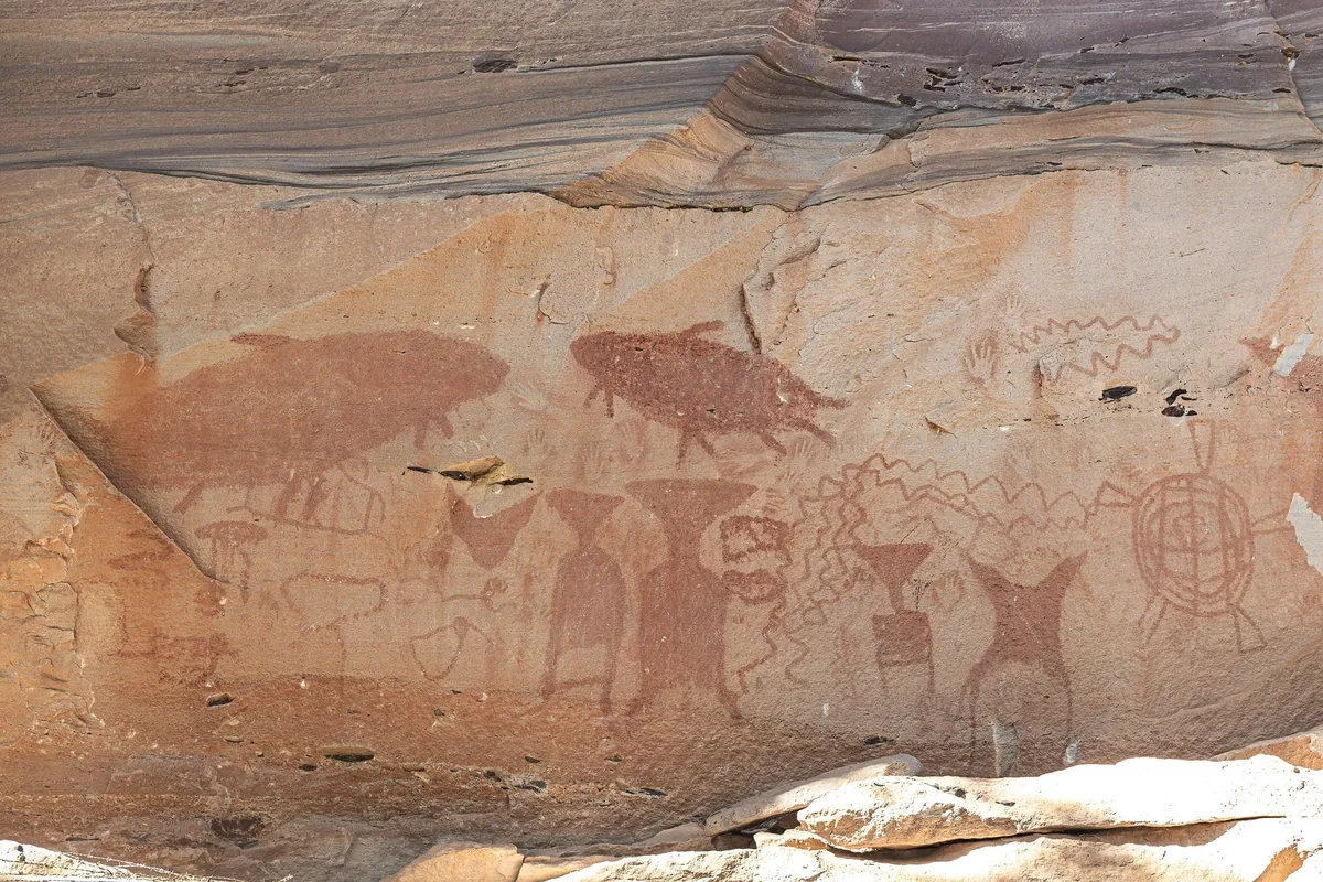 Prehistoric red ochre paintings of giant catfish, figures and hand prints on the sandstone cliff at Pha Taem National Park