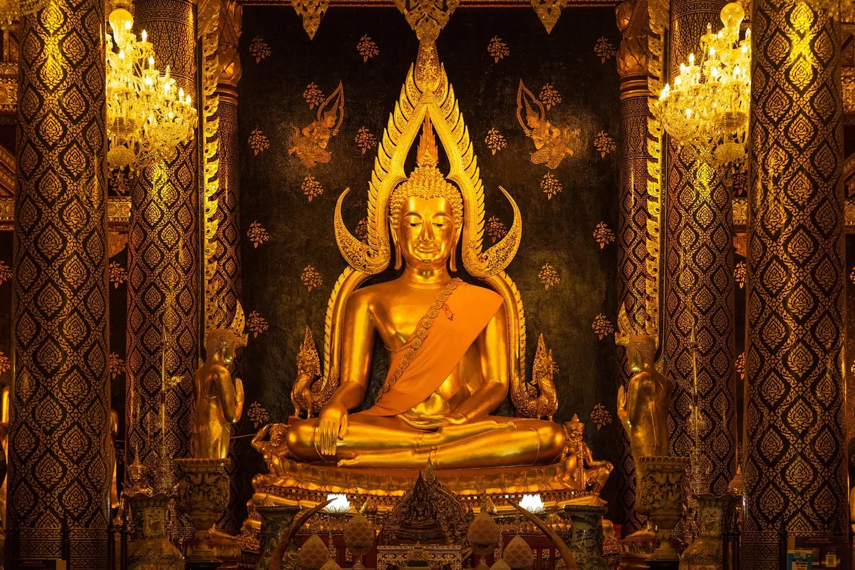 The gilded Phra Phuttha Chinnarat Buddha with its flame-shaped halo inside the main hall of Wat Yai, Phitsanulok