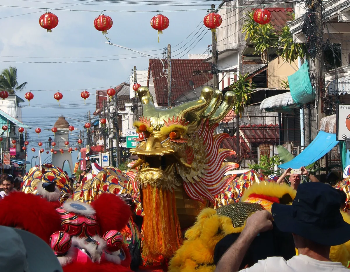 Golden dragon dance under strings of red lanterns in Maenam's Chinatown street, Koh Samui, at Chinese New Year