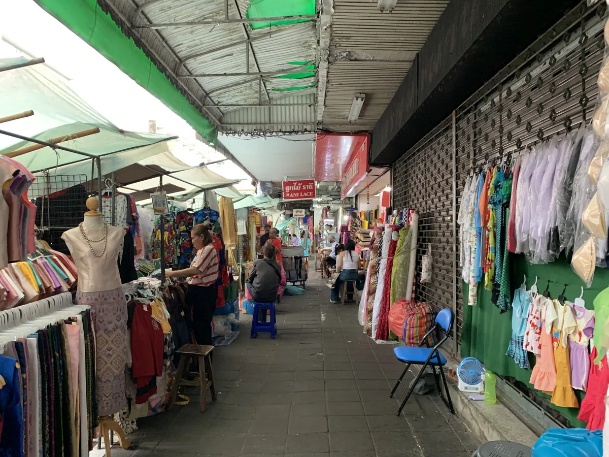 Covered market lane in Phahurat, Bangkok's fabric district, lined with dress mannequins, cloth bolts and stalls