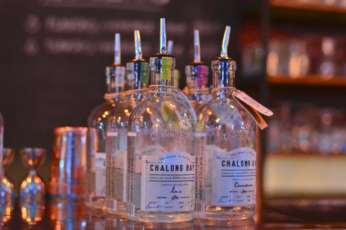 Bottles of Chalong Bay, a sugarcane spirit labelled The Spirit of Phuket, lined up on a bar counter