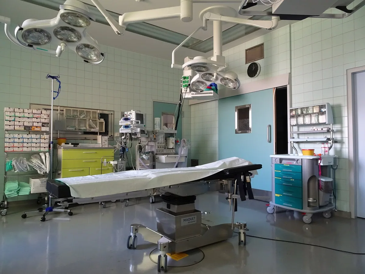 Empty, prepared operating room with a draped operating table under ceiling-mounted surgical lights