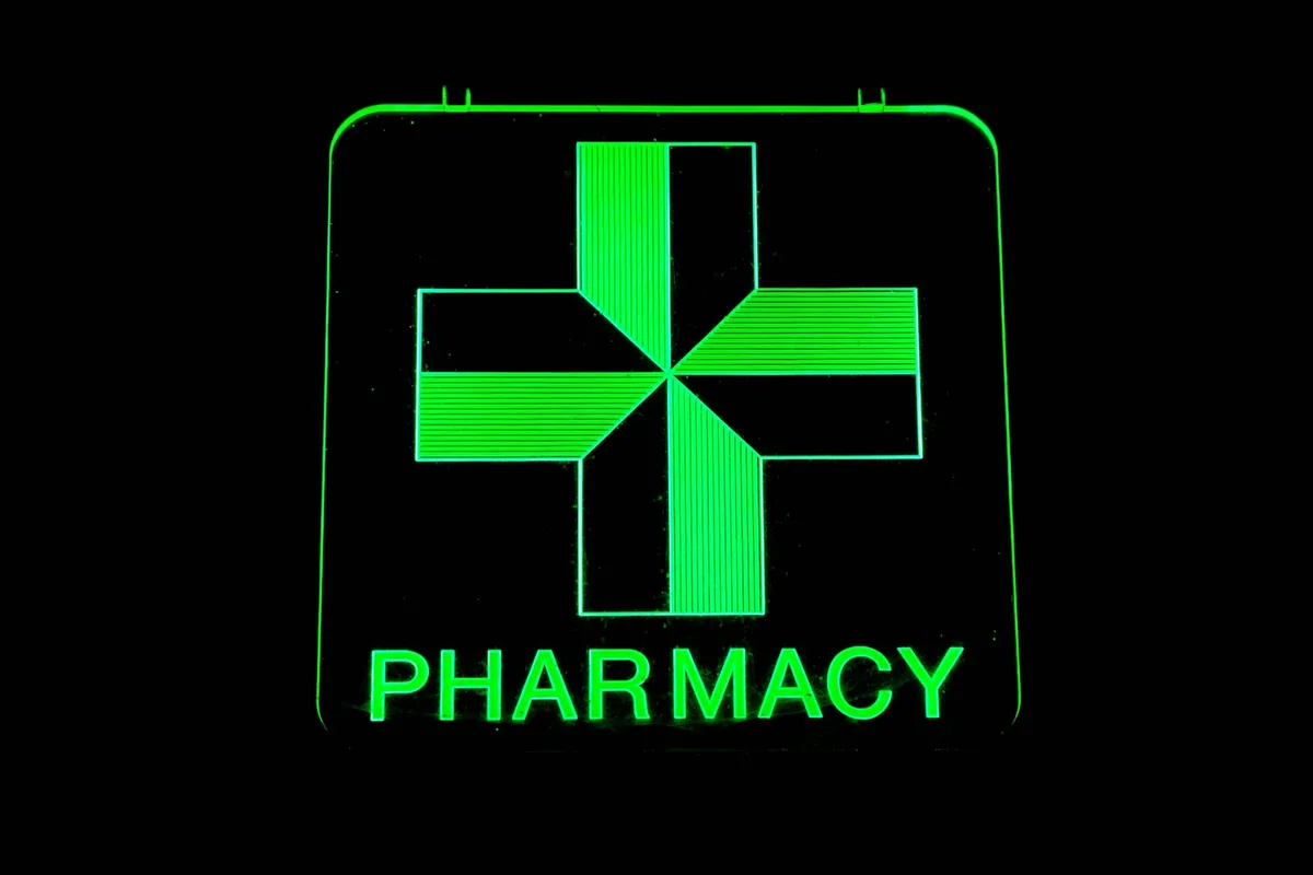 Illuminated green cross pharmacy sign glowing against the dark night sky