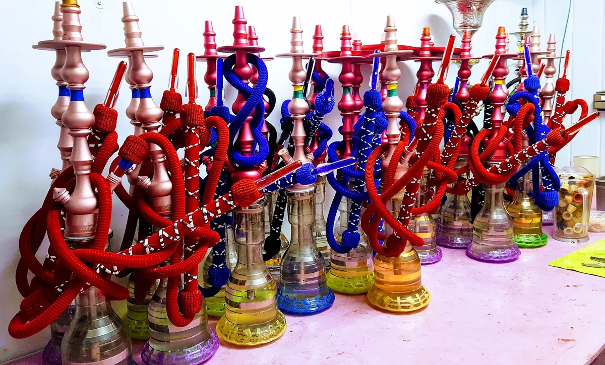 Rows of colourful hookah pipes with red and blue hoses lined up on a table