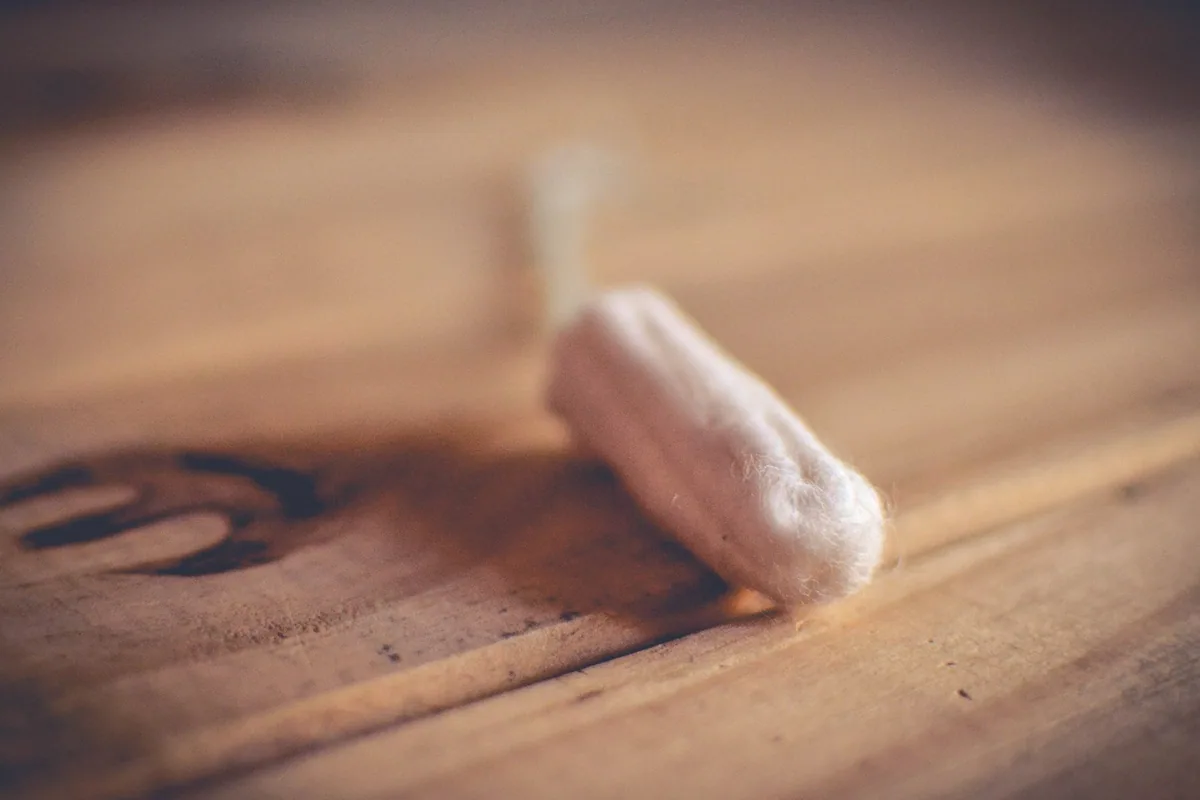 A single unwrapped tampon lying on a wooden table in soft light