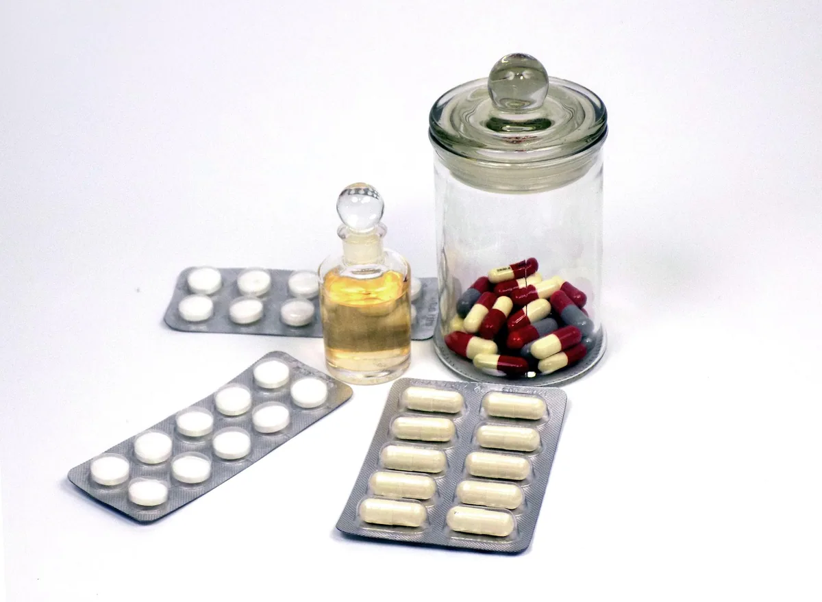 Blister packs of tablets, a glass jar of capsules and a small bottle of liquid medicine