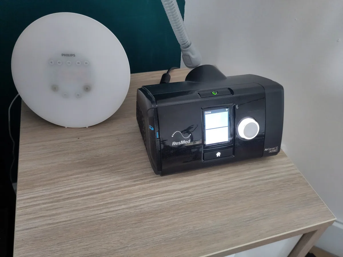 A CPAP machine with its hose on a bedside table