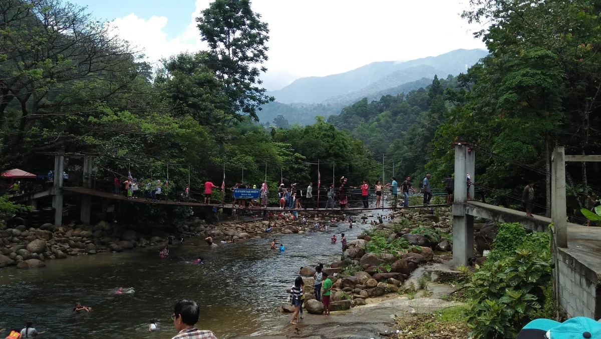 Swimmers in a rocky mountain stream below a suspension bridge at Kiriwong, Khao Luang National Park