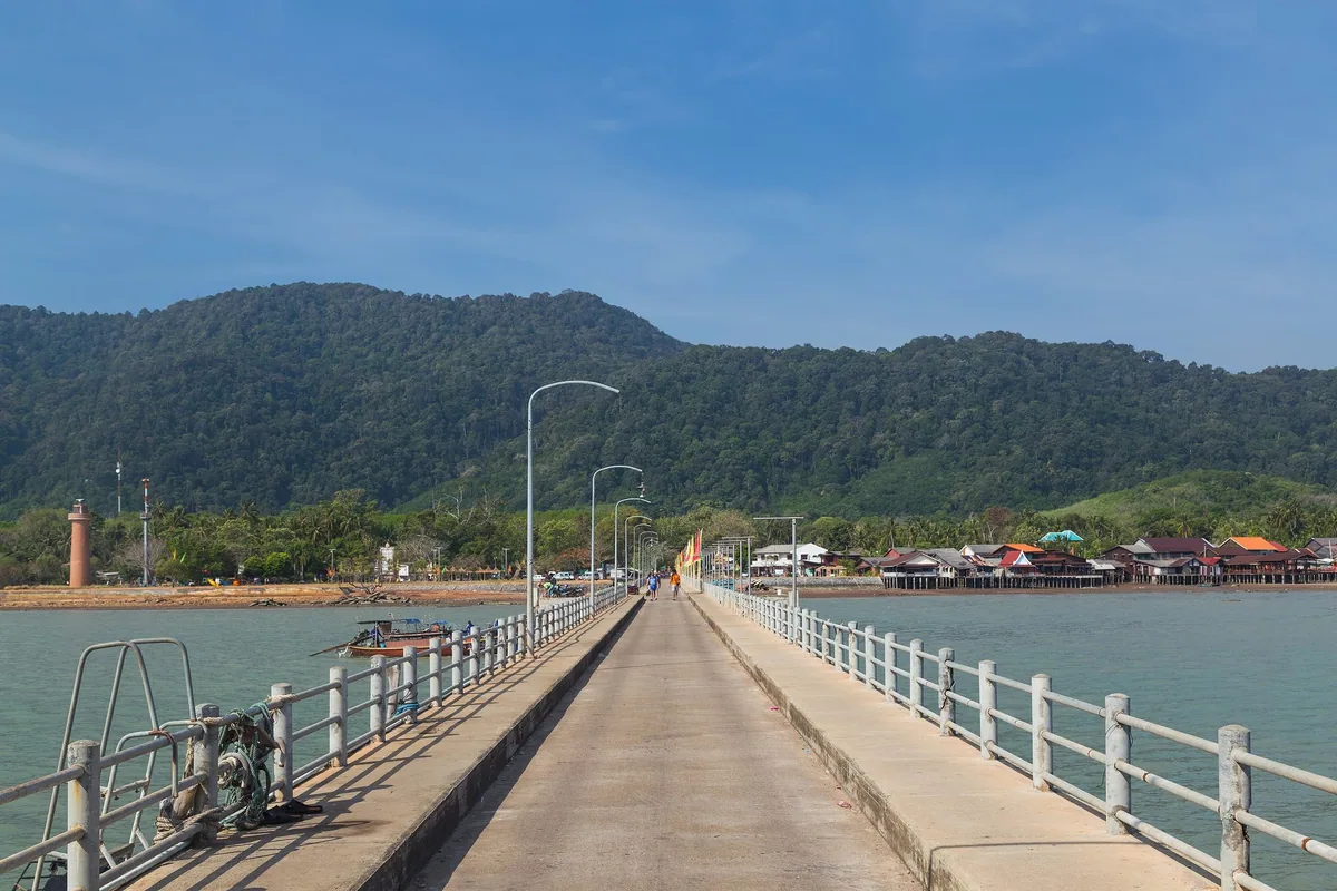Long pier at Lanta Old Town on Koh Lanta's east coast, with stilt houses and forested hills behind