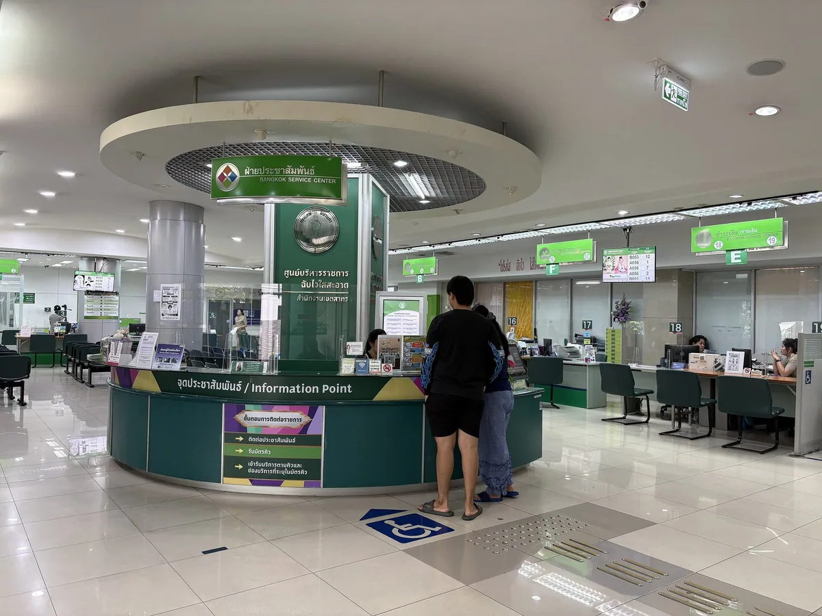 Information desk, numbered service counters and a queue-number screen inside the Sathon District Office, Bangkok
