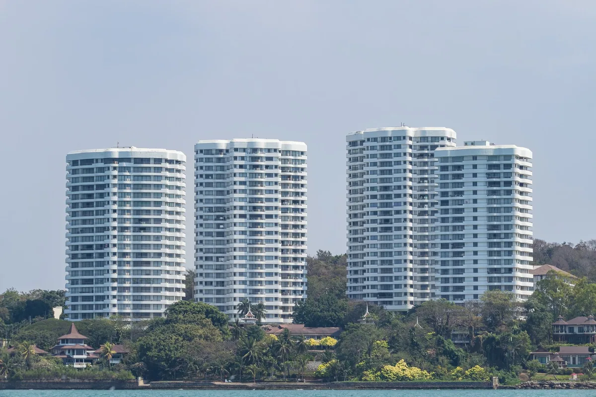 Four white high-rise condominium towers rising behind trees on the seafront at Royal Cliff Garden in Pattaya