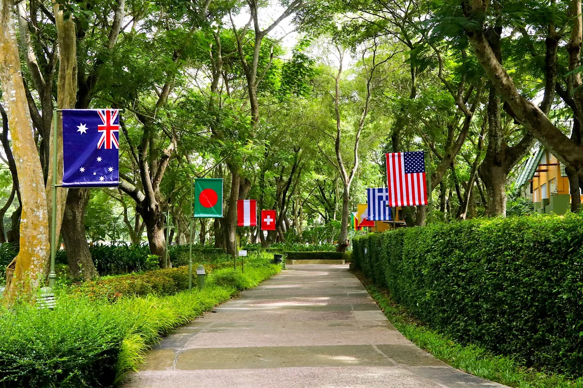 Tree-shaded walkway lined with national flags on the campus of Prem Tinsulanonda International School near Chiang Mai