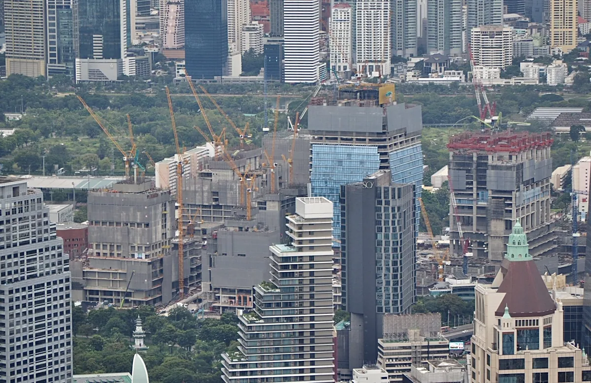 Tower cranes over a large construction site surrounded by condominium and office towers in central Bangkok
