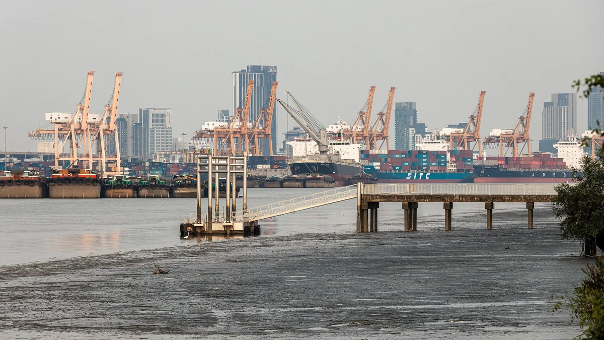 Container cranes and cargo ships at Bangkok Port in Khlong Toei, seen across the Chao Phraya River