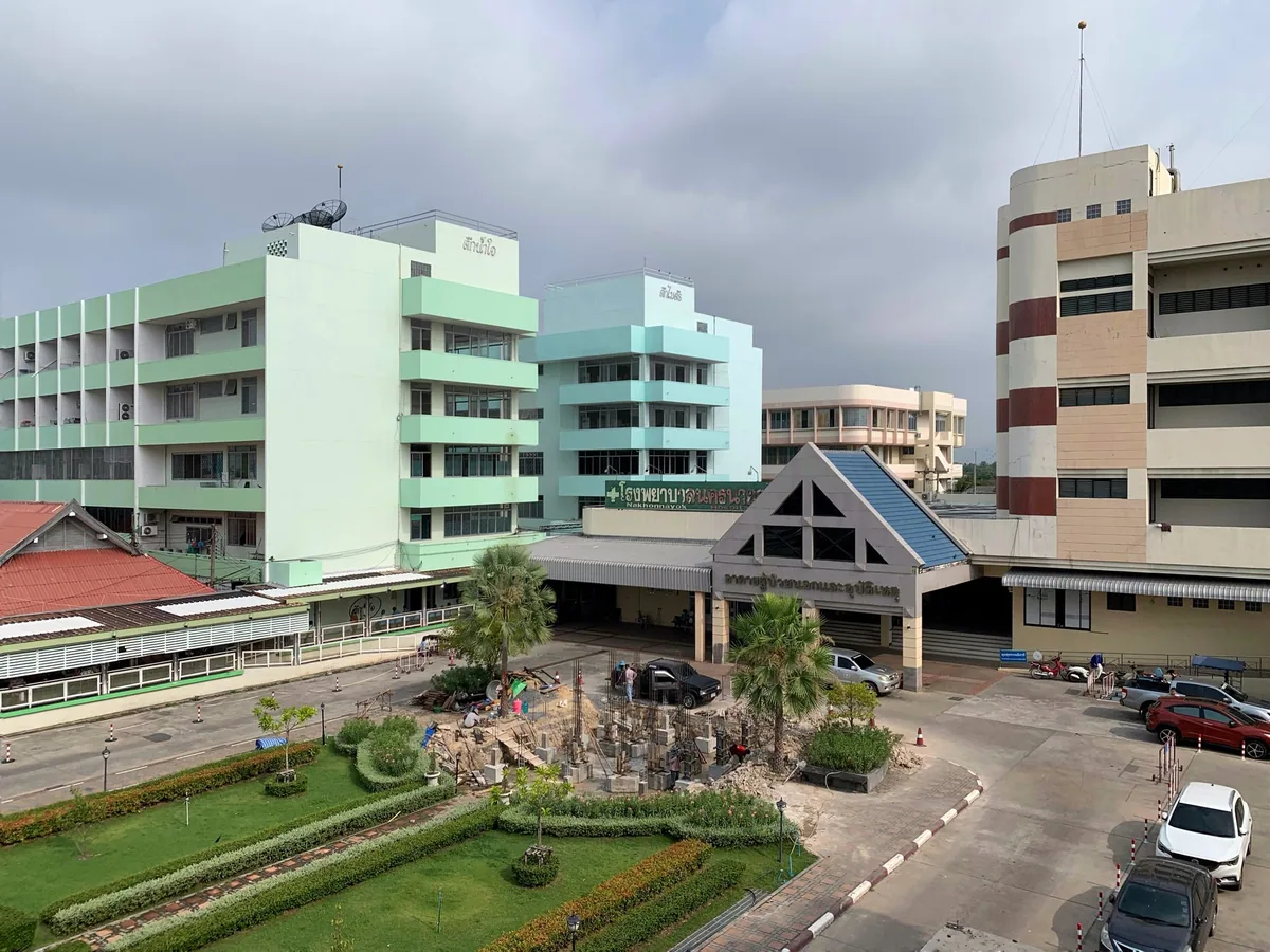 Pale green ward buildings and the main entrance of Nakhon Nayok Hospital, a Thai public hospital