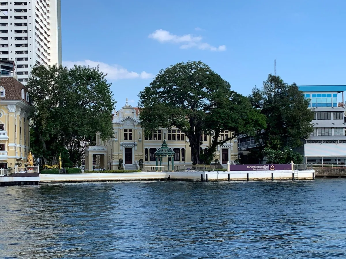 The historic Siam Commercial Bank Talat Noi branch among old trees on the Chao Phraya riverbank in Bangkok