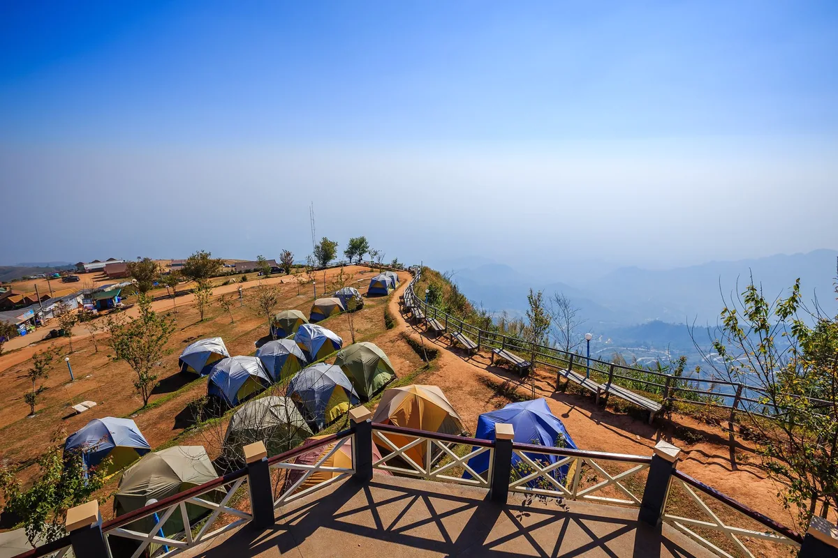 Rows of hire tents on a ridge-top campsite at Phu Thap Boek, Phu Hin Rong Kla National Park, above hazy mountains