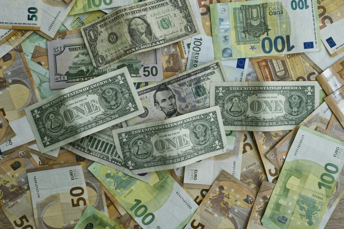 US dollar bills and euro banknotes of various denominations scattered together on a table