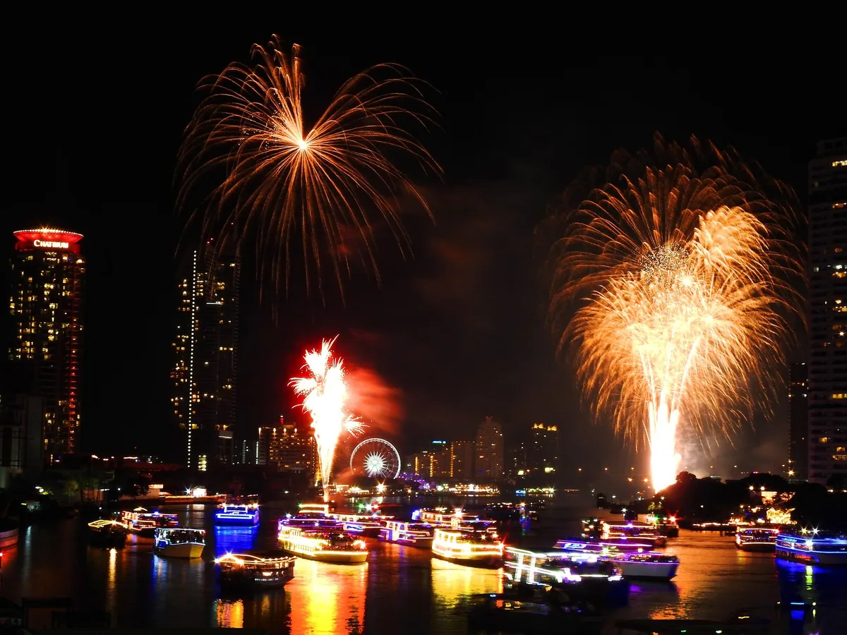 New Year's Eve fireworks bursting over illuminated boats on the Chao Phraya River in Bangkok
