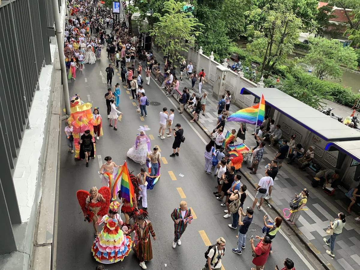 Costumed marchers and rainbow flags moving along a Bangkok street during the 2024 Pride parade