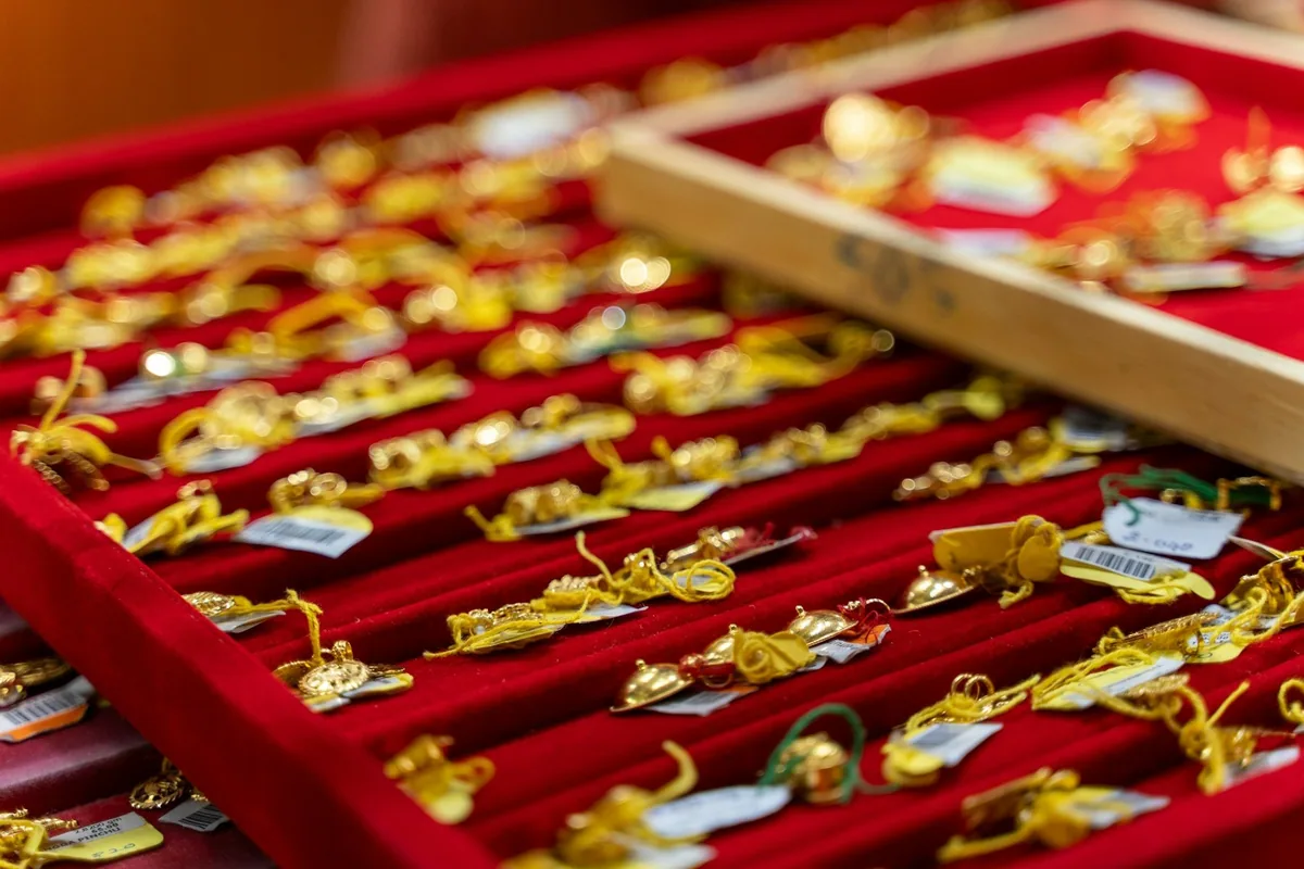Trays of tagged gold rings and pendants on red velvet in a jeweller's display counter