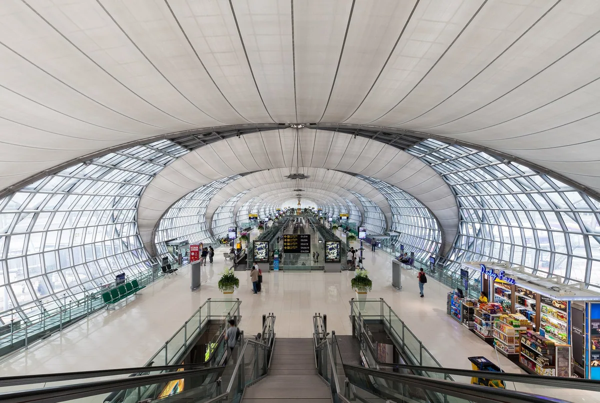 Curved glass-and-steel roof over a departure concourse at Suvarnabhumi Airport, Bangkok