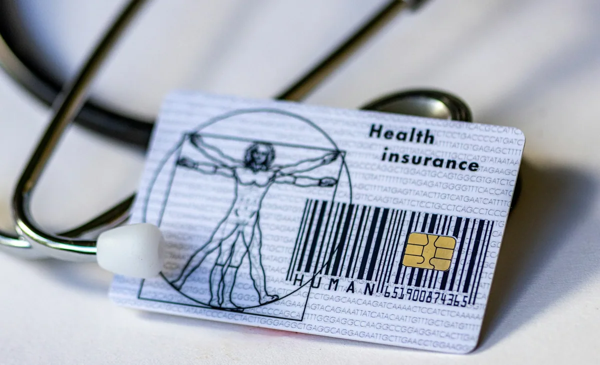 A health insurance card lying beside a stethoscope