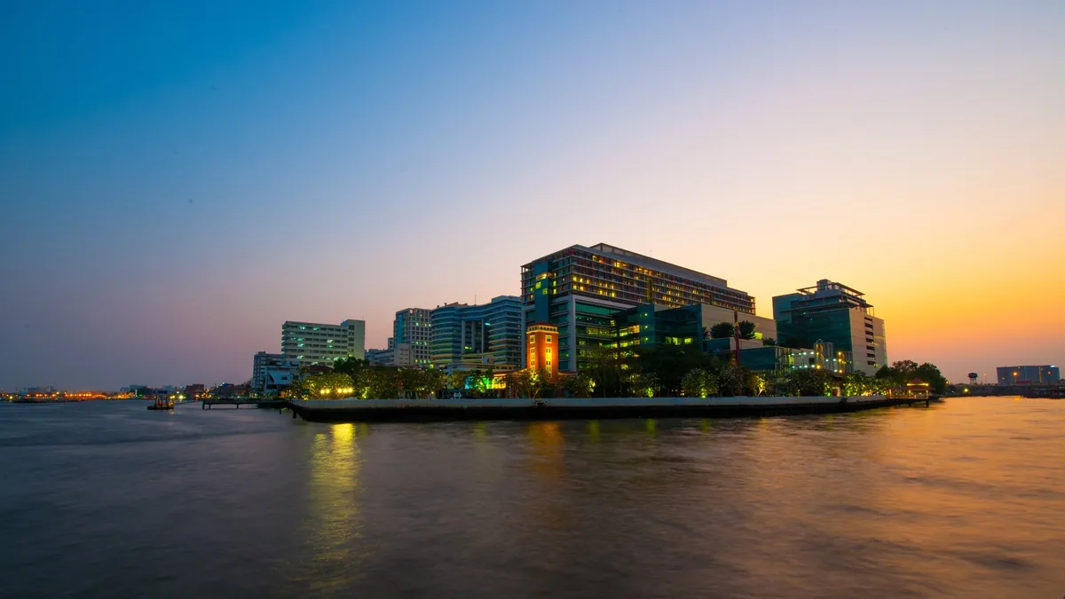 Siriraj Hospital buildings on the Chao Phraya riverbank in Bangkok at dusk