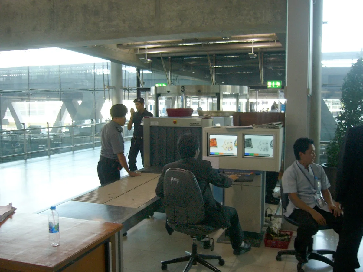 Security staff at an X-ray baggage scanner on the departure level of Suvarnabhumi Airport in Bangkok