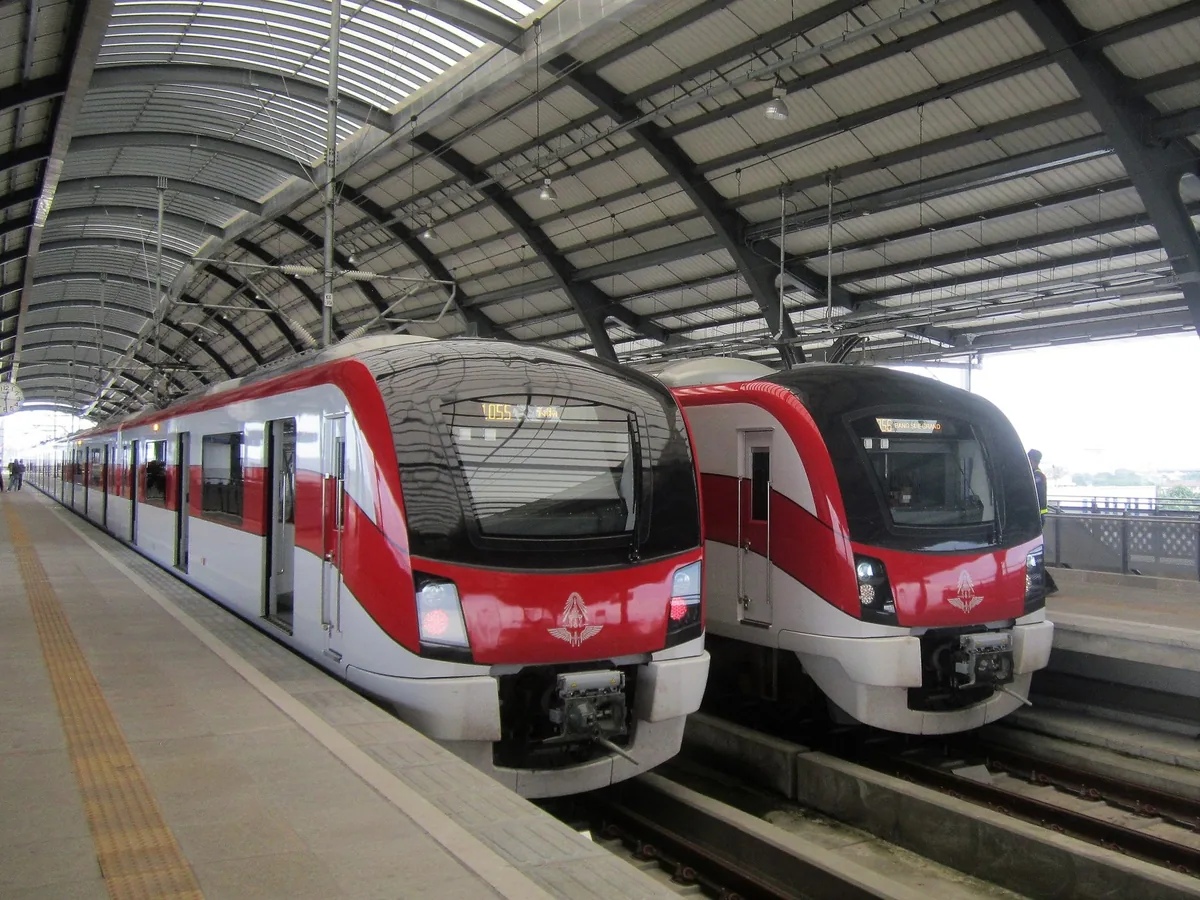 Two red-and-white SRT Dark Red Line commuter trains side by side under the arched roof of Rangsit station