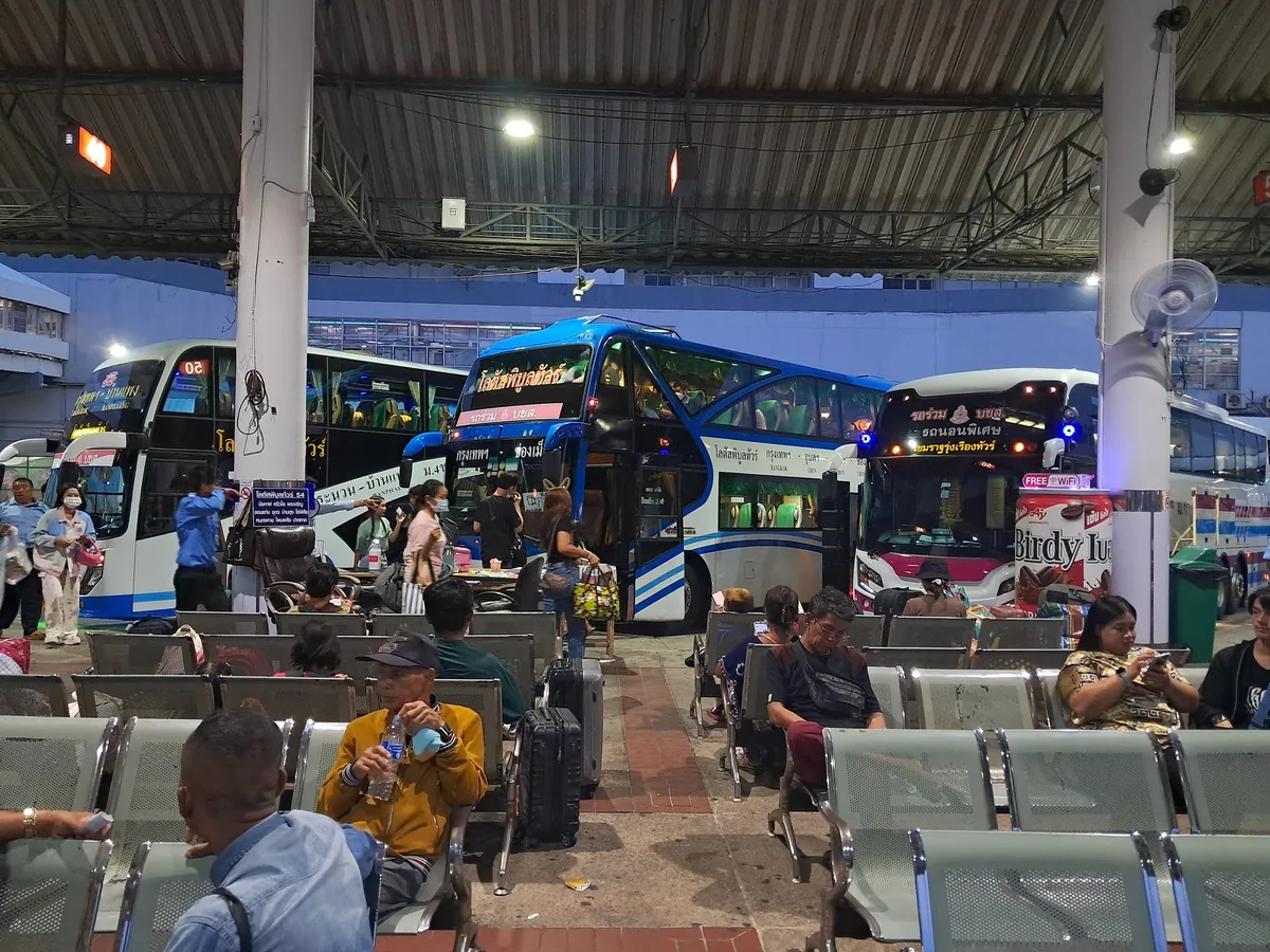Passengers waiting beside double-decker coaches at Mo Chit 2 bus terminal, Bangkok