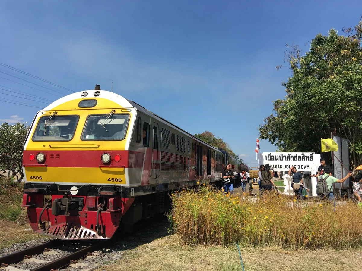 A red and yellow SRT diesel locomotive pulling the weekend excursion train into the Pa Sak Jolasid Dam halt